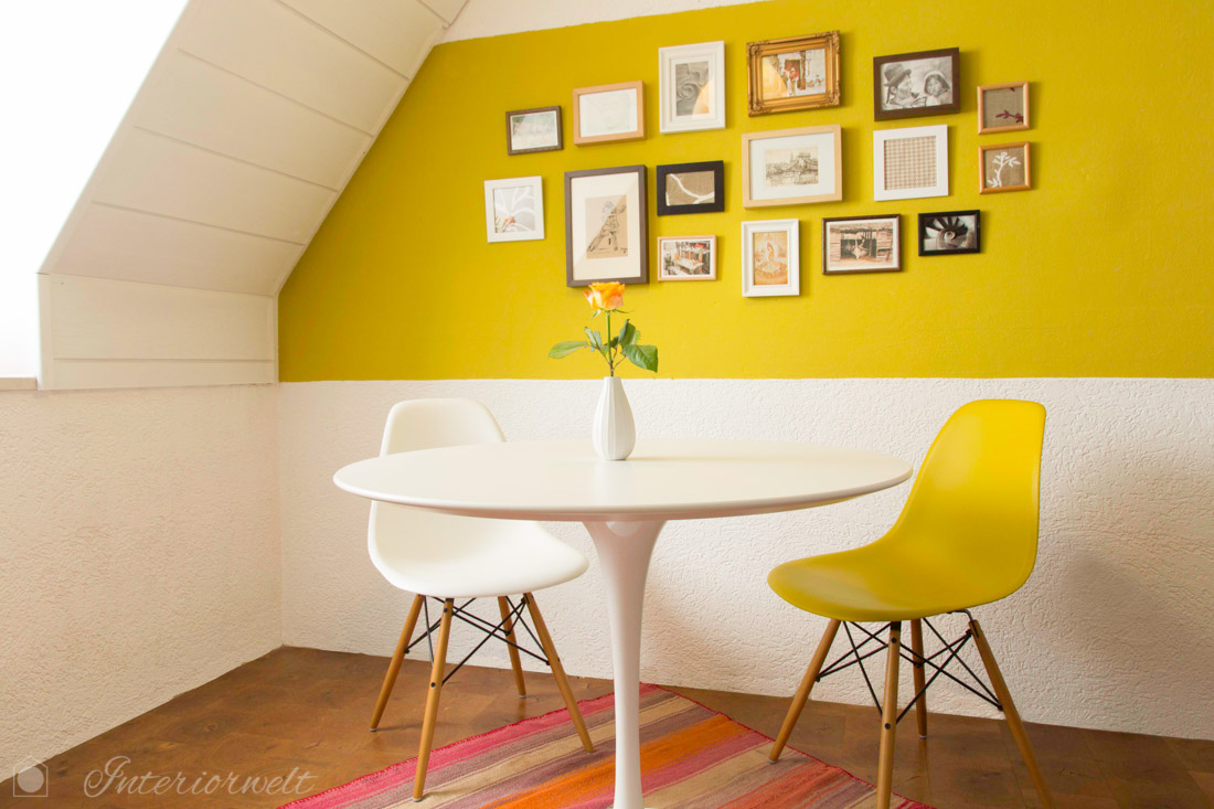 Esstisch und gelb-grüne Wand mit Bildern